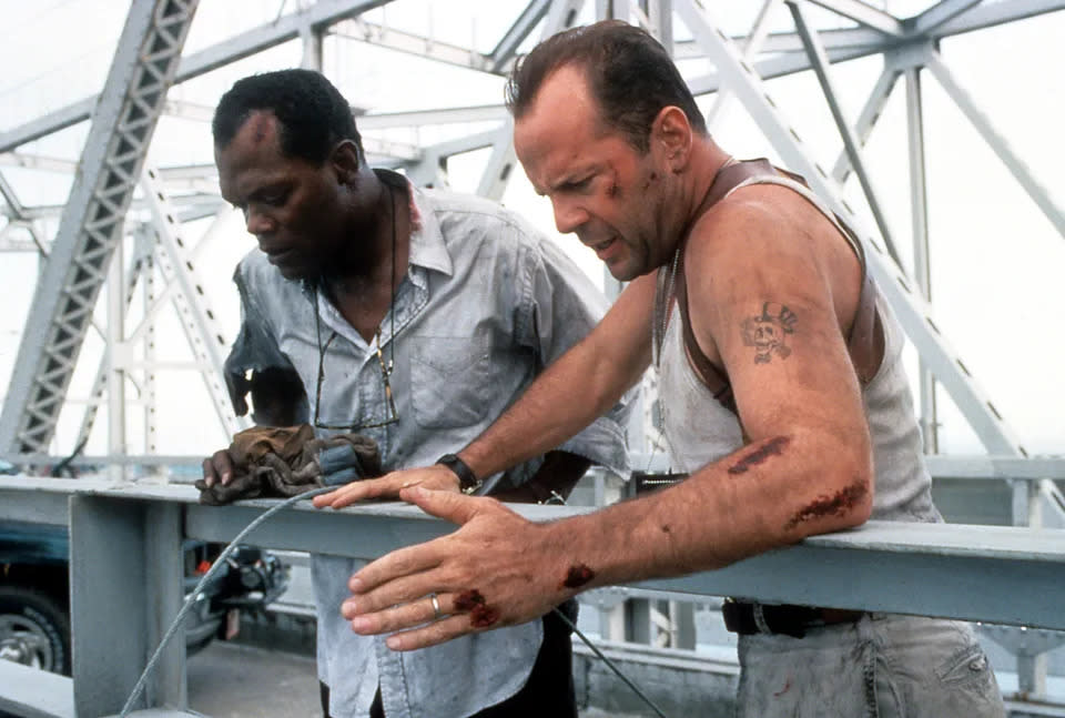 Samuel L. Jackson und Bruce Willis stehen auf einer Brücke und blicken nach unten in einer Szene aus dem Film 