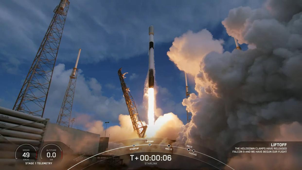  spacex rocket lifting off amid launch towers with a plume of steam rising to the right 
