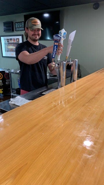 Reid Elwood serves a draft beer at Woody’s Bar & Grill. A portion of the 25-foot cypress bar is shown in the foreground.