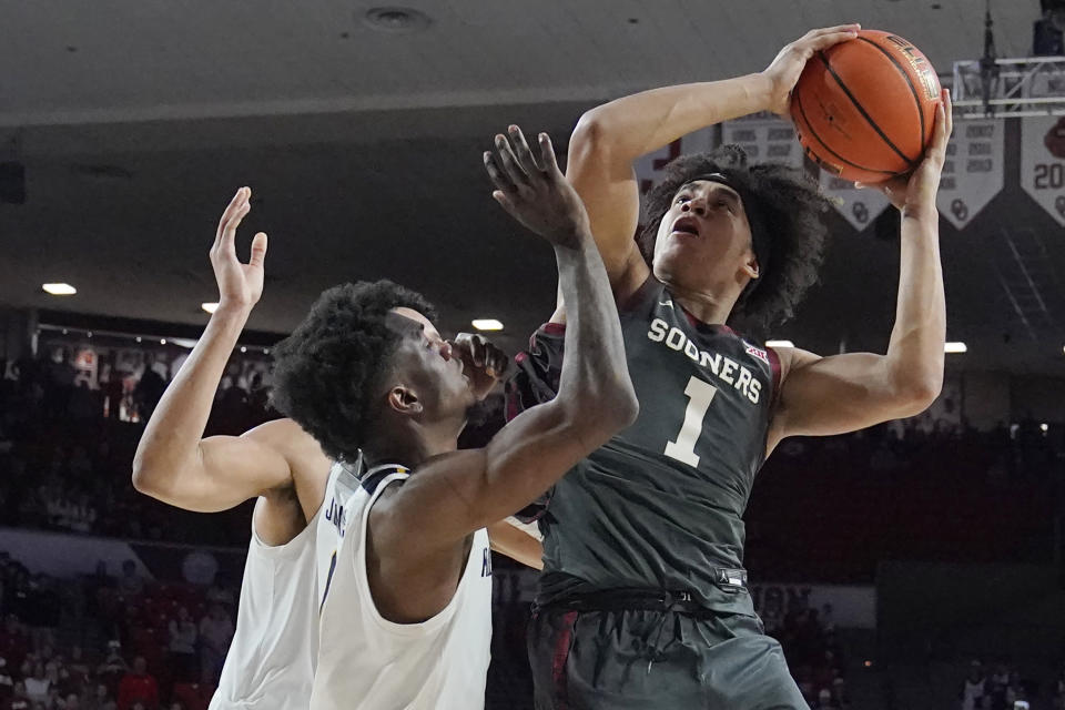 Oklahoma forward Jalen Hill (1) shoots as West Virginia guard Kedrian Johnson, left, defends, in the second half of an NCAA college basketball game Saturday, Jan. 14, 2023, in Norman, Okla. (AP Photo/Sue Ogrocki)