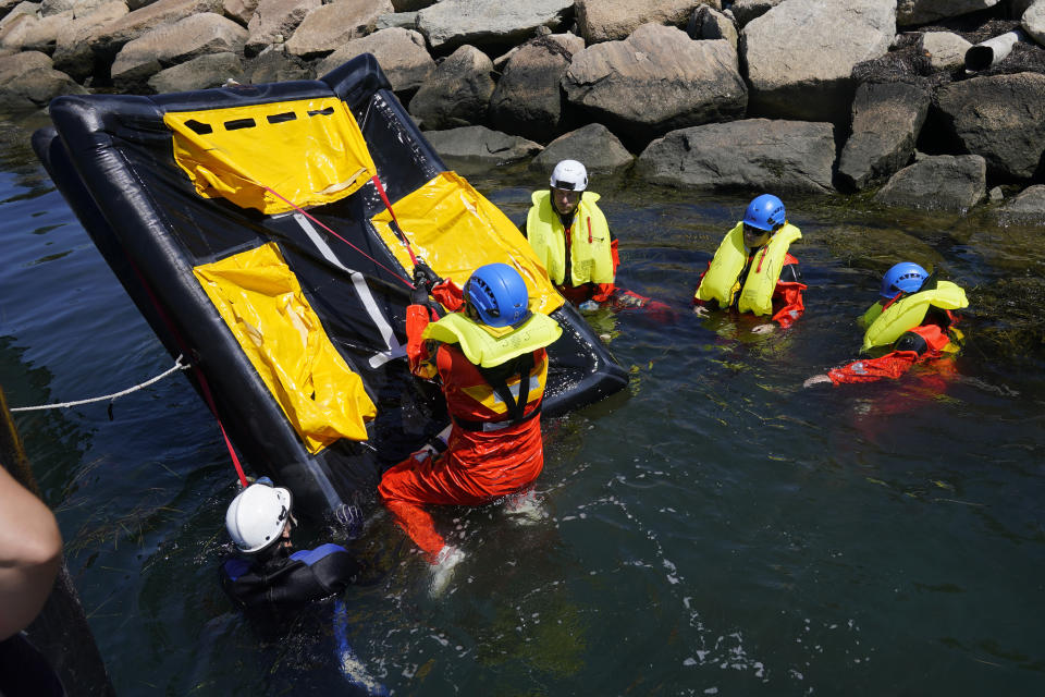 Students practice flipping a life raft, in case it is deployed upside down, during a Global Wind Organisation certification class at the Massachusetts Maritime Academy in Bourne, Mass., Thursday, Aug. 4, 2022. At the 131-year-old maritime academy along Buzzards Bay, people who will build the nation's first commercial-scale offshore wind farm are learning the skills to stay safe while working around turbines at sea. (AP Photo/Seth Wenig)