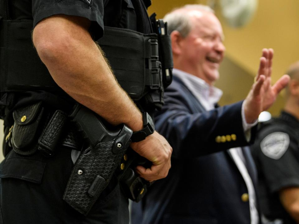 Flanked by two armed Evansville Police Department officers, U.S. Rep. Larry Bucshon, back, meets his constituents following a town hall meeting, in which he answered questions for about an hour and a half, at the Southern Indiana Career & Technical Center in Evansville, Ind., Monday evening, Aug. 19, 2019. He cited security concerns and expenses as a reason for not holding town halls more often. 