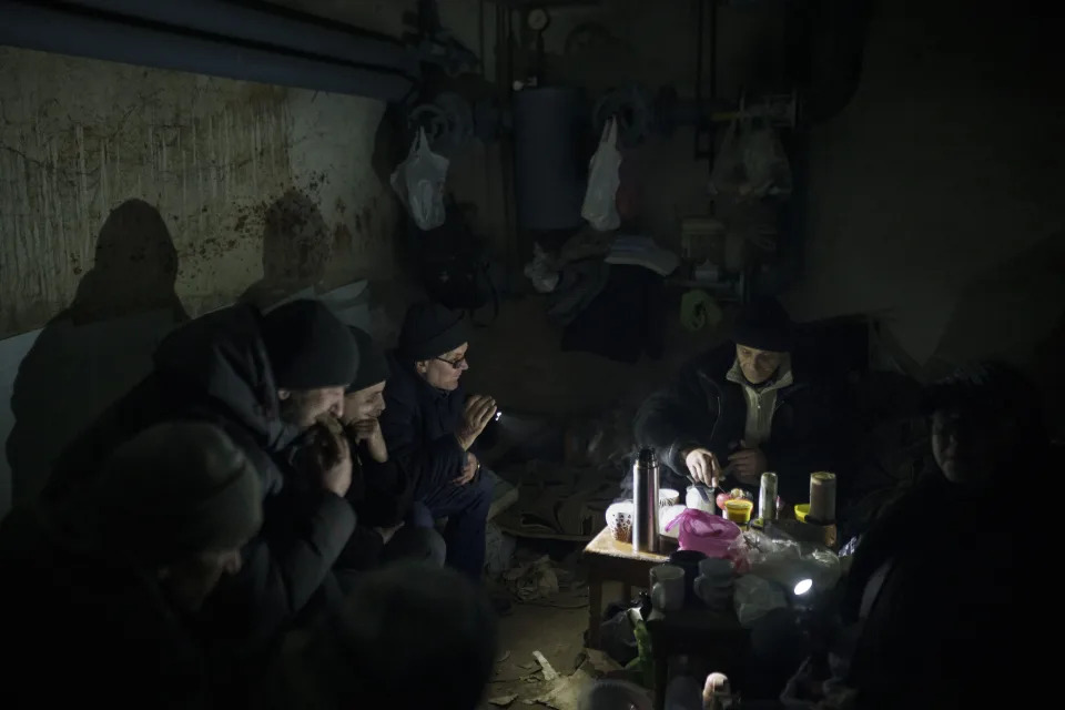 Residents prepare tea as they sit in a basement being used as a bomb shelter in Irpin, outskirts of Kyiv, Ukraine, Sunday, March 13, 2022. (AP Photo/Felipe Dana)