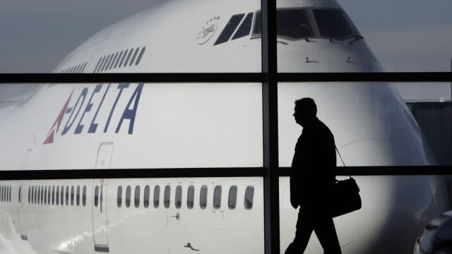 A person is seen near a Delta Air Lines plane.