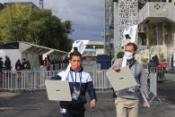 Volunteers wearing face masks to prevent the spread of coronavirus while carrying hand-sanitizer dispensers at at the Roland Garros stadium in Paris, Friday, Sept. 25, 2020. Already repeatedly trimmed, crowd sizes for the French Open have been reduced again to just 1,000 spectators per day because of the worsening coronavirus epidemic in Paris. (AP Photo/Michel Euler)