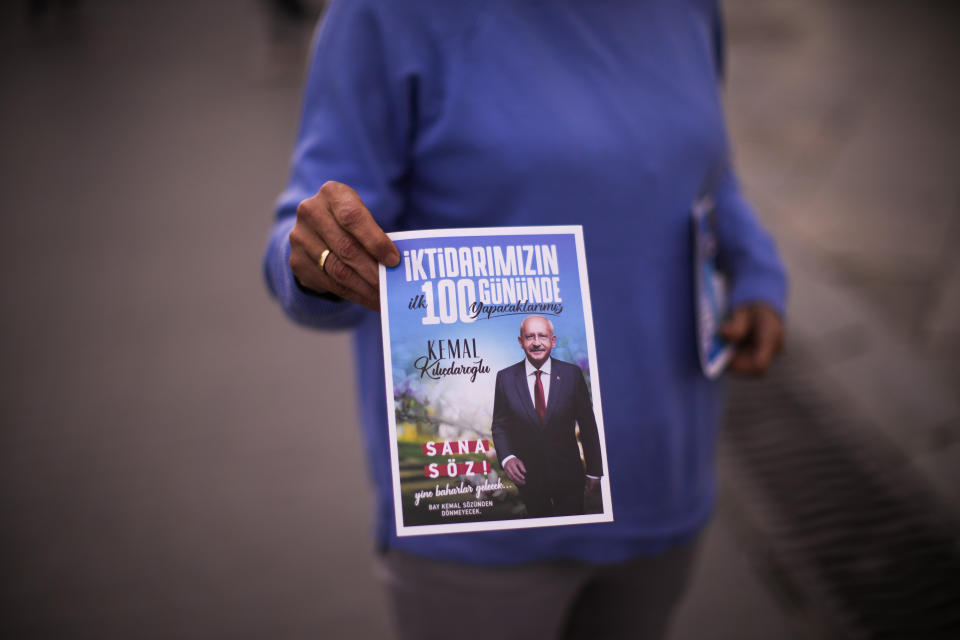 A woman gives election handouts of Turkish CHP party leader and Nation Alliance's presidential candidate Kemal Kilicdaroglu to commuters, in Istanbul, Turkey, Tuesday, April 18, 2023. Turkey is heading toward presidential and parliamentary elections on Sunday May 14, 2023. (AP Photo/Francisco Seco)