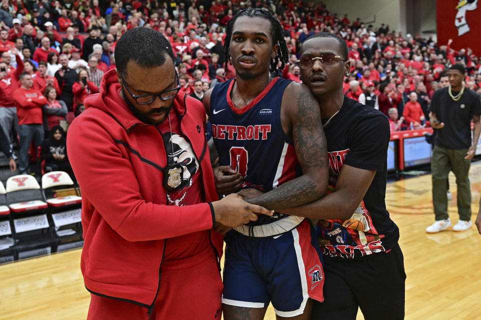 Detroit Mercy guard Antoine Davis, center, is assisted off the floor by bodyguard Daniel Toomer, left, and manager Nathan Harrison, right, after his team was defeated by Youngstown State in an NCAA college basketball game in the quarterfinals of the Horizon League tournament, Thursday, March 2, 2023, in Youngstown, Ohio.(AP Photo/David Dermer)