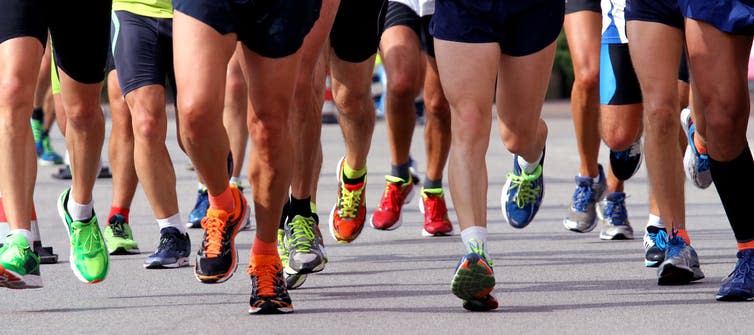 Many runners' legs and shoes running on tarmac