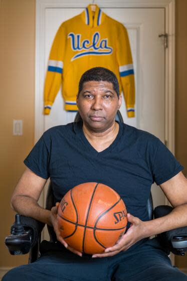 Former UCLA basketball star Rod Foster holds a basketball and sits in his wheelchair in his West L.A. home.