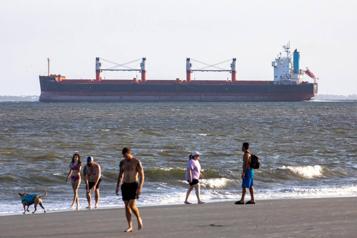 A ship passes through Charleston harbor as beachgoers walk Sullivan’s Island. Shifting sands are having opposite effects on some Charleston area beaches with erosion claiming the Folly Beach shoreline while Sullivan Island’s beach is growing. July 21, 2022.