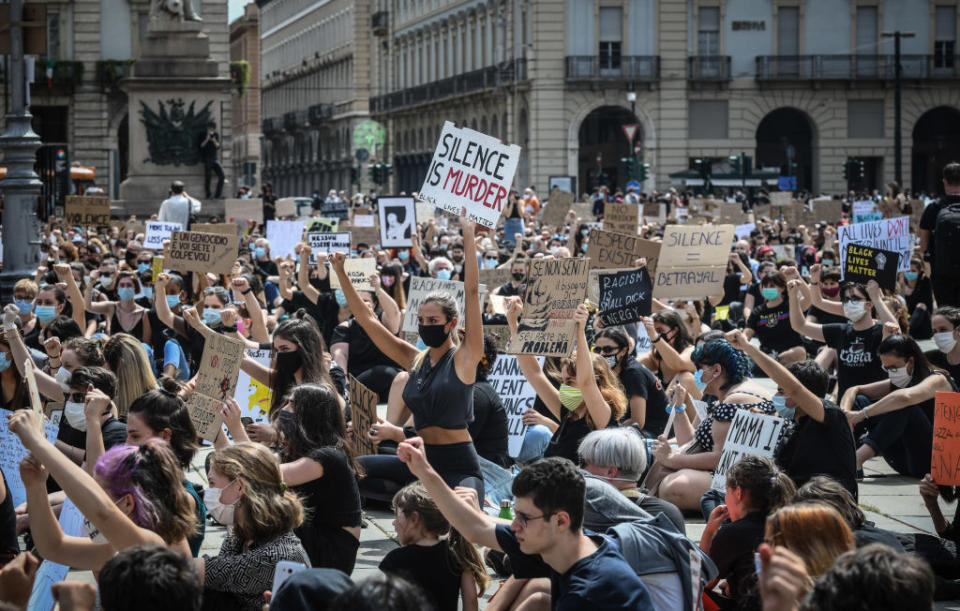 Crowd of protesters kneeling and holding signs for justice and against violence