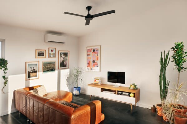 The couple's living room, anchored by a favorite old leather sofa, stays cool with the help of a ceiling fan and mini-split heating and cooling unit.