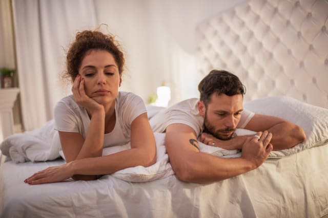 Depressed couple having relationship problems in their bed.