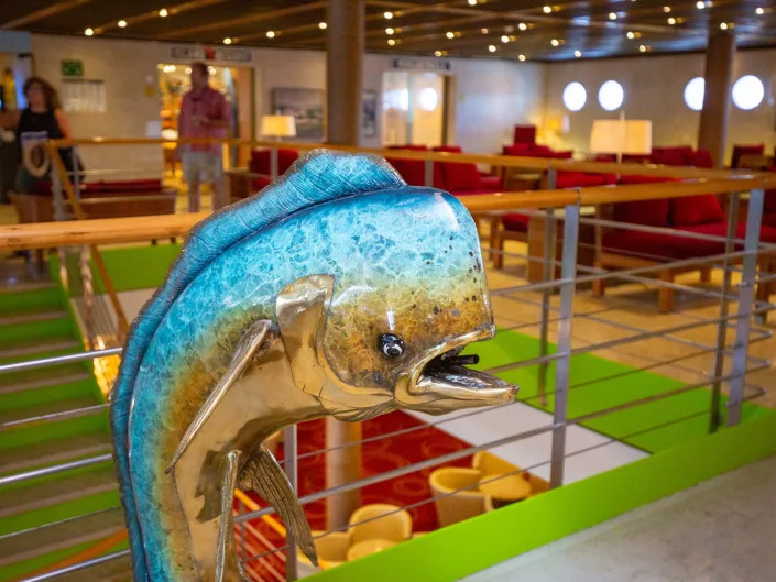 A statue of a fish next to a staircase, lounge chairs.