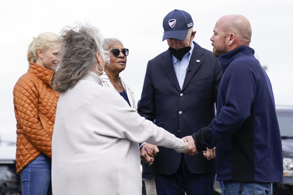 President Joe Biden bows his head as he holds hands Jesse Perry, Graves County Judge Executive, right, and Anne Henning Byfield, Presiding Bishop of the AME Council of Bishops, third from right, in Mayfield, Ky., Wednesday, Dec. 15, 2021. Mayfield Mayor Kathy Stewart O'Nan is second from left. (AP Photo/Andrew Harnik)