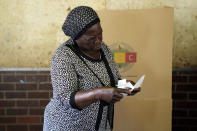 A woman scrutinizes ballot papers before casting her vote at a polling station in Harare, Zimbabwe, Wednesday, Aug. 23, 2023. Polls have opened in Zimbabwe as President President Emmerson Mnangagwa seeks a second and final term in a country with a history of violent and disputed votes. (AP Photo/Tsvangirayi Mukwazhi)