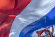 Supporter of Thailand's monarchy lift a giant national flag during a gathering stating their concern over the country's pro-democracy movement which they feel besmirches the royal institution in Bangkok, Thailand, Thursday, July 30, 2020. The demonstration was held at Democracy Monument, a traditional venue for protests of all political stripes that in recent weeks has hosted several larger pro-democracy, anti-government protests organized by students. (AP Photo/Sakchai Lalit)