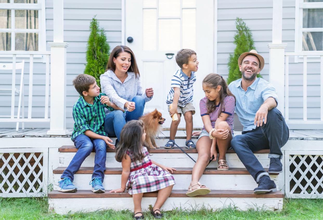 family with a dog sitting on front steps of their house