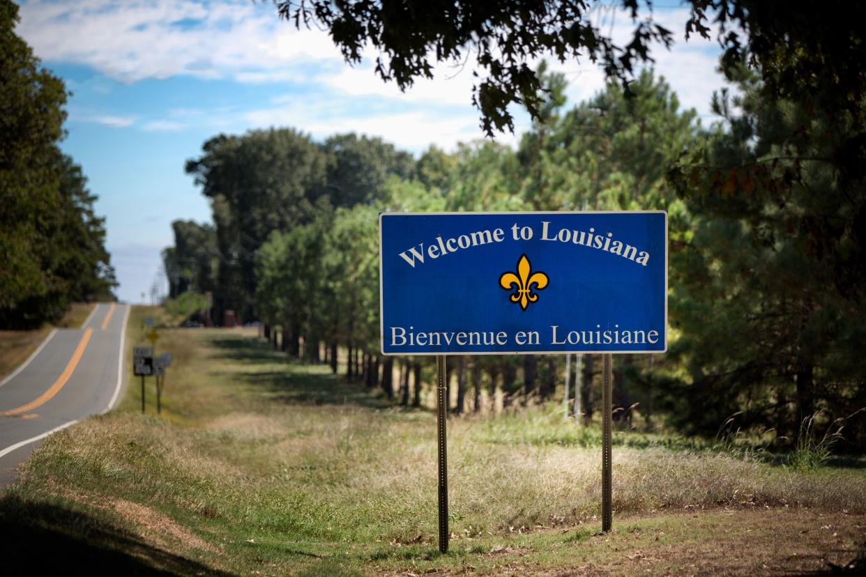 Remote location state line from Texas to Louisiana on a two lane highway with a sign welcoming travelers into the state of Louisiana. The sign also has the French version, Bienvenue in Louisiane.