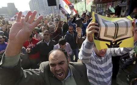 People shout slogans against the military and interior ministry, hold up an image of the Koran and flash the Rabaa sign during an Islamist protest in the Cairo suburb of Matariya November 28, 2014. REUTERS/Mohamed Abd El Ghany