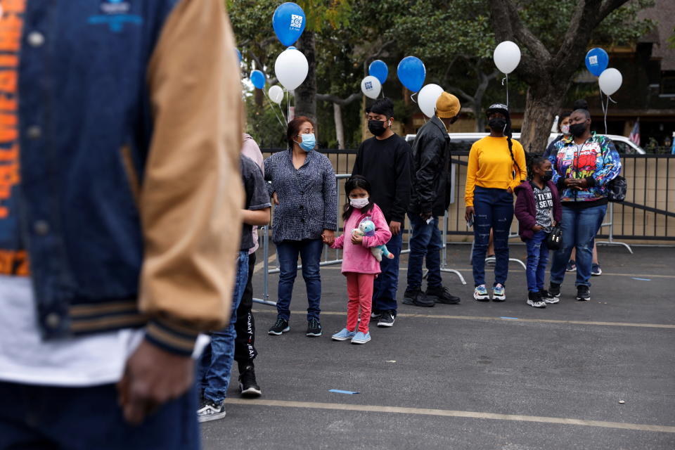 People wearing protective face masks wait in line to receive available first, second and booster doses of the COVID-19 vaccine at the L.A. Care Health Plan free testing and vaccination site.