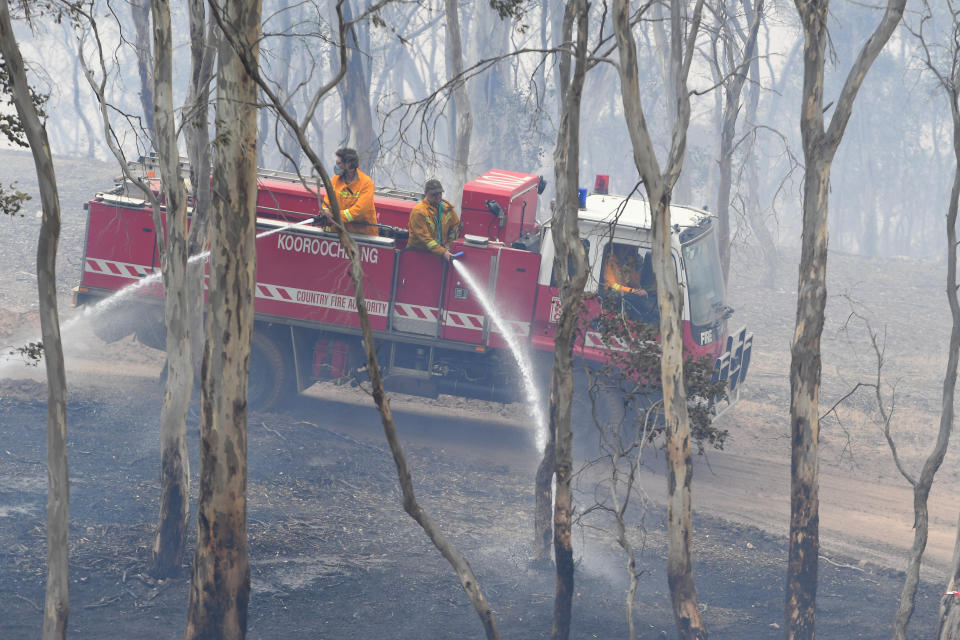 CFA firefighters are seen spraying water onto smouldering bushland at Mount Glasgow, Victoria.