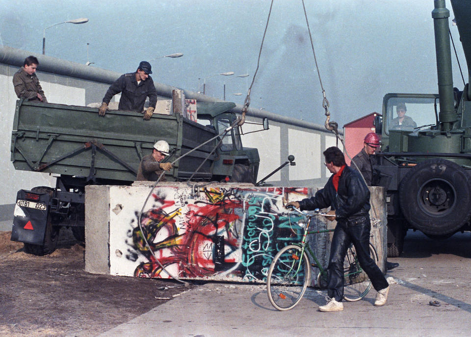 East German workers remove concrete parts of the Berlin Wall and load them onto trucks at the recently opened border crossing point at Potsdam Platz on Nov. 14, 1989. (Photo: Wolfgang Rattay/Reuters)