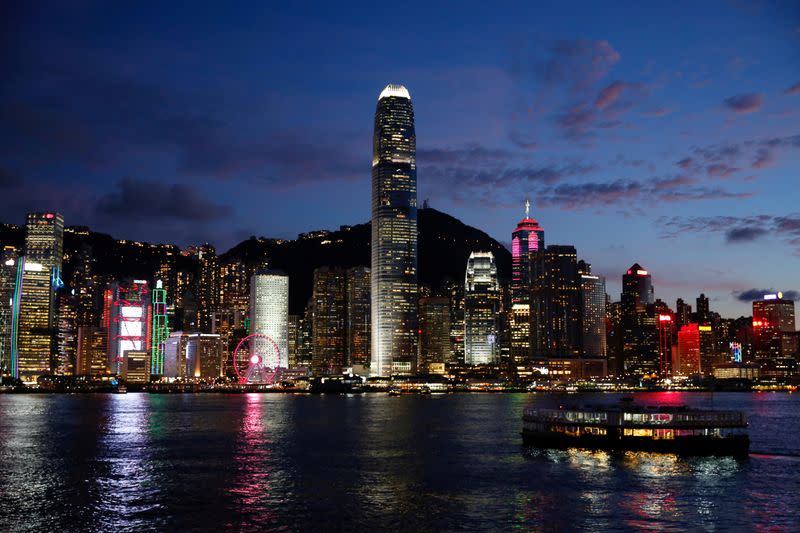 FILE PHOTO: A Star Ferry boat crosses Victoria Harbour in front of a skyline of buildings during sunset.