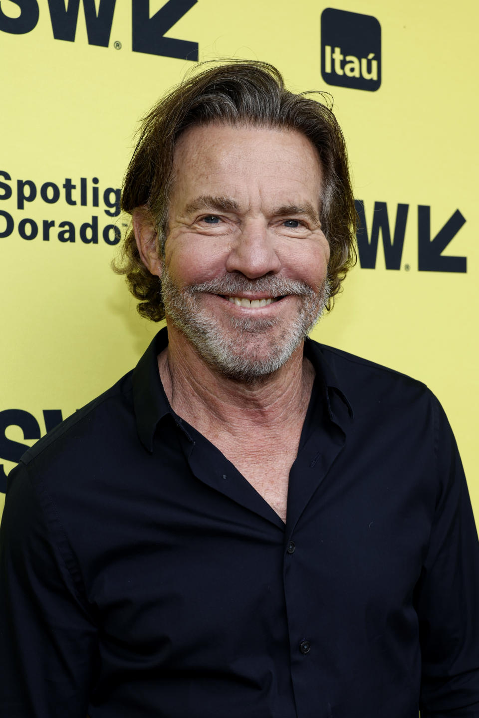 Dennis Quaid smiles at a SXSW event, wearing a casual dark shirt