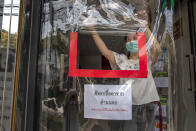 A pharmacist opens a service window through a plastic sheet covering the entrance to help practice social distancing in Bangkok, Thailand, Thursday, April 2, 2020. A state of emergency has been declared in the country to allow the government to impose stricter measures to control the coronavirus that has infected hundreds of people in the region. The new coronavirus causes mild or moderate symptoms for most people, but for some, especially older adults and people with existing health problems, it can cause more severe illness or death. (AP Photo/Gemunu Amarasinghe)