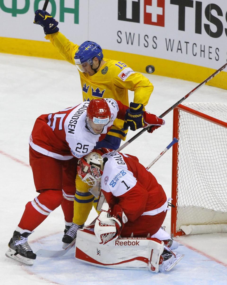 Denmark's Patrick Galbraith, bottom, Oliver Lauridsen, center, and Sweden's Mattias Sjogren battle for the puck during the Group A preliminary round match between Denmark and Sweden at the Ice Hockey World Championship in Minsk, Belarus, Saturday, May 10, 2014. (AP Photo/Sergei Grits)