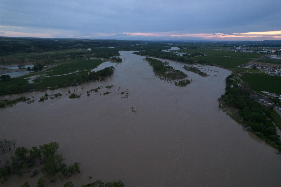 The roaring Yellowstone River is seen from the air sweeping over trees and near homes Tuesday, June 14, 2022, in Billings, Mont. (AP Photo/Brittany Peterson)