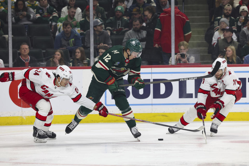 Minnesota Wild left wing Matt Boldy (12) goes after the puck against Carolina Hurricanes center Seth Jarvis (24) and center Jordan Staal (11) during the first period of an NHL hockey game Tuesday, Feb. 27, 2024, in St. Paul, Minn. (AP Photo/Stacy Bengs)
