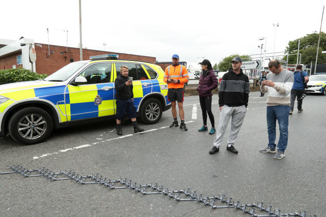 LEEDS, ENGLAND - JULY 04: Protesters take photos as the police block off the exit of Ferrybridge service station with a stinger on July 04, 2022 in Leeds, England. Prices for petrol and diesel have risen steadily this year as the price of oil has climbed, due to post-pandemic demand and sanctions against Russia, one of the world's largest oil exporters. (Photo by Cameron Smith/Getty Images)