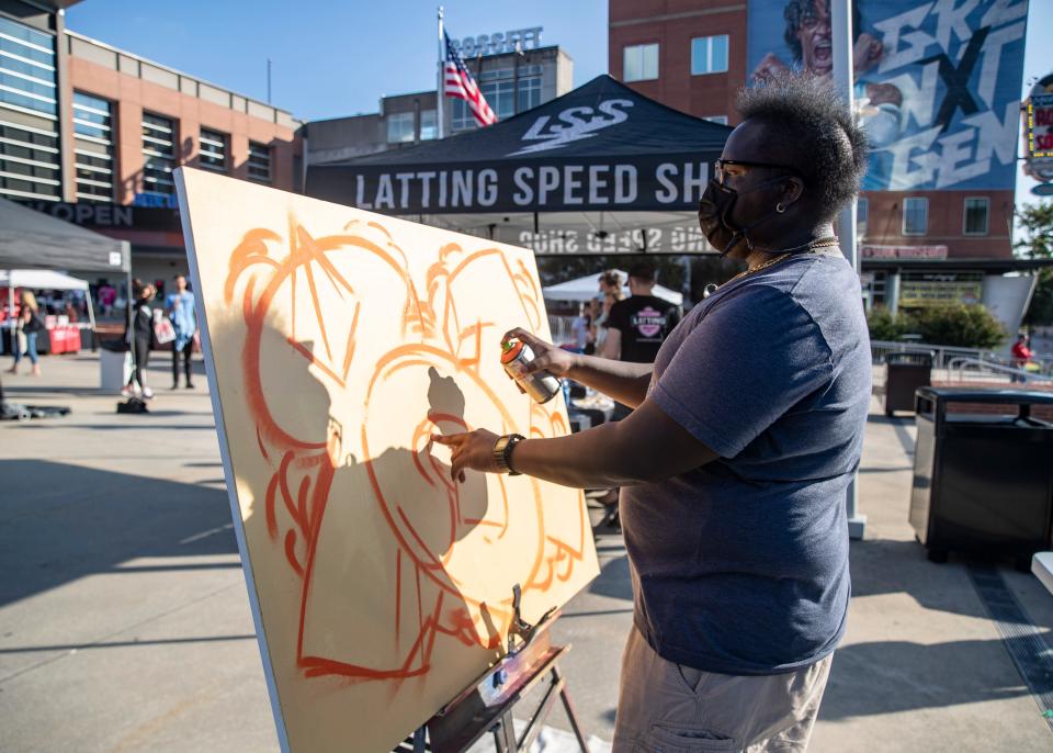 Local artist Quantavious Worship sprays paint onto a canvas during the 901 Day Exposure event at the FedExForum courtyard on Sept. 1, 2021.