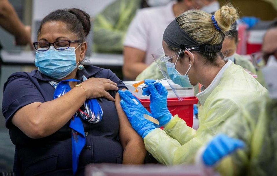 Shanta Seojatan, left, who works for American Airlines, gets her Pfizer vaccine at the pop-up vaccination site in Concourse D in the 4th floor auditorium at Miami International Airport on May 9, 2021. The vaccines will be available to airport employees, their family and friends, and travelers living or working in Florida from 8 a.m. to 5 p.m. through May 14, then June 1 through 4, and June 7, according to airport officials. There will be two locations at MIA: Concourse D in the 4th floor auditorium; and a drive through at 75 Bus Road in Miami (MIA taxi overflow lot).