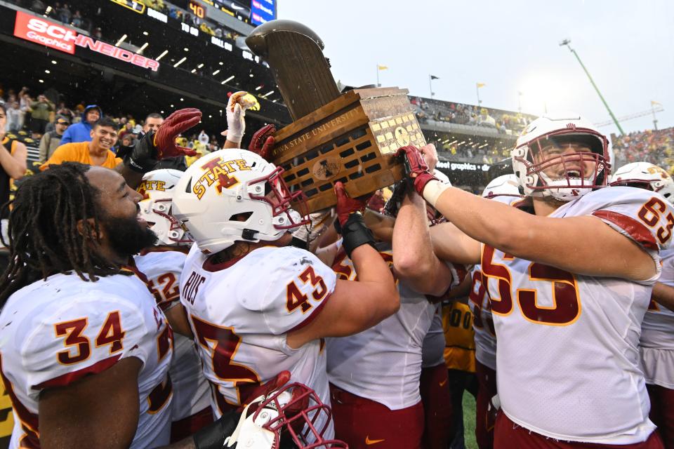 The Iowa State Cyclones lift the Cy-Hawk Trophy after defeating rival Iowa.