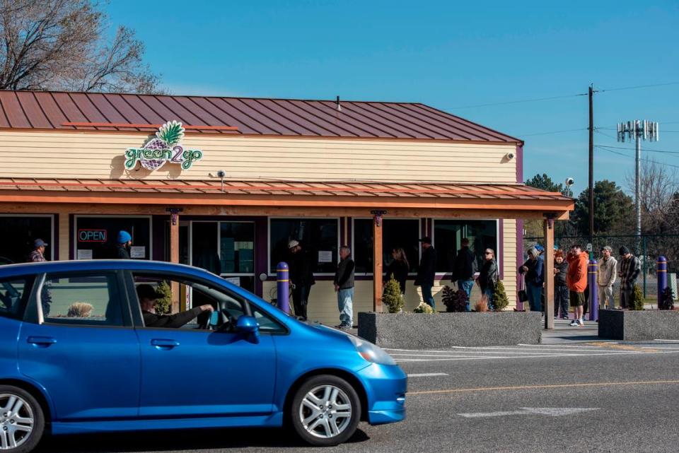 A line of customers wraps around the building at the cannabis retailer, Green2Go, on March 18.  According to business owner, Steve Lee, customers are told to stand three to six feet apart in line and are limited to 10 or fewer people in the building at a time.