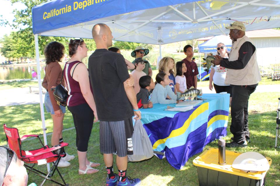 A CDFW Fishing in the City volunteer speaks at one of the five clinic stations at Granite Regional Park in Sacramento on May 15, 2024.