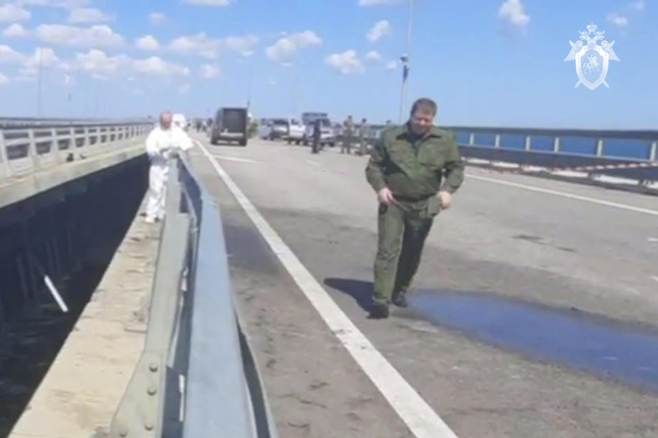 In this handout photo taken from video released by Investigative Committee of Russia on Monday, July 17, 2023, investigators work at an automobile link of the Crimean Bridge connecting Russian mainland and Crimean peninsula over the Kerch Strait not far from Kerch, Crimea. Traffic on the key bridge connecting Crimea to Russia's mainland was halted on Monday, July 17, after reports of explosions that Crimean officials said were from a Ukrainian attack. (Investigative Committee of Russia via AP)