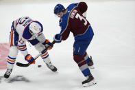 Edmonton Oilers center Mattias Janmark, left, and Colorado Avalanche defenseman Jack Johnson go after the puck during the first period of an NHL hockey game Thursday, April 18, 2024, in Denver. (AP Photo/David Zalubowski)