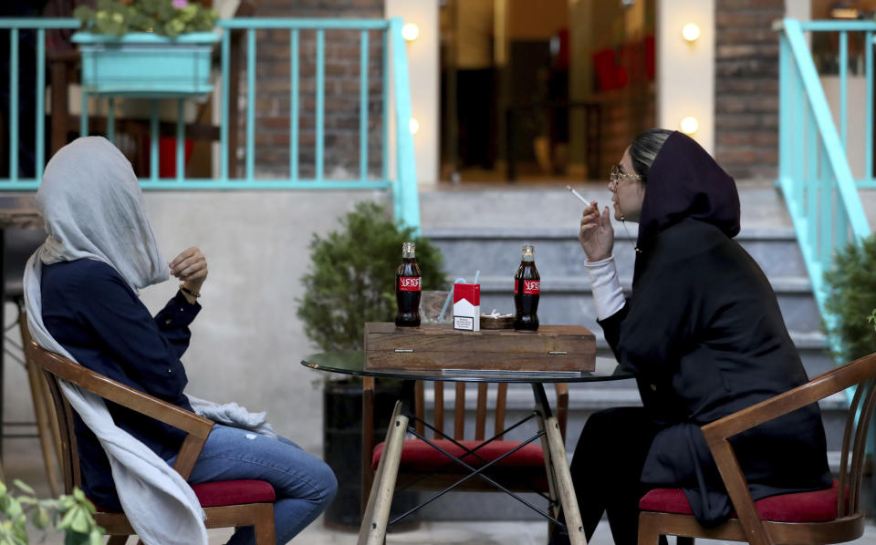 An Iranian smokes a Marlboro cigarette while two Coca-Cola stand on her table at a cafe in downtown Tehran, Iran, Wednesday, July 10, 2019. Whether at upscale restaurants or corner stores, American brands like Coca-Cola and Pepsi can be seen throughout Iran despite the heightened tensions between the two countries. U.S. sanctions have taken a heavy toll, but Western food, movies, music and clothing are still widely available. (AP Photo/Ebrahim Noroozi)