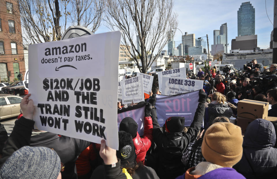 FILE - In this Nov. 14, 2018, file photo protesters carry anti-Amazon posters during a coalition rally and press conference opposing Amazon headquarters getting subsidies to locate in the New York neighborhood of Long Island City in the Queens borough of New York. Some residents wondered why one of the world's most valuable companies needed nearly $3 million in tax incentives to come to New York. (AP Photo/Bebeto Matthews, File)