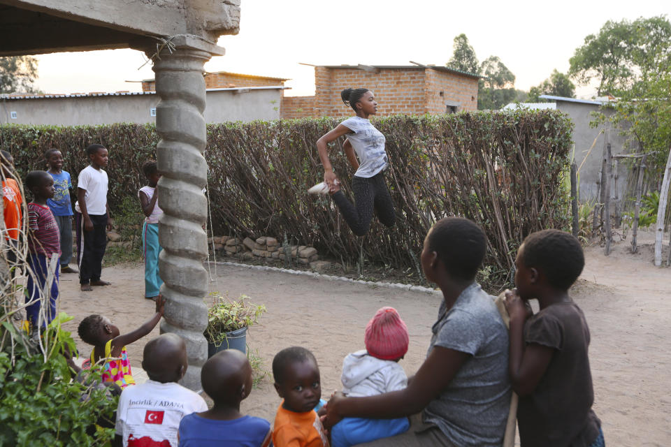 Children and young mothers watch as Natsiraishe Maritsa, center, goes through stretching and a warm up before a taekwondo practice session with young boys and girls in the Epworth settlement about 15 km southeast of the capital Harare, Saturday Nov. 7, 2020. In Zimbabwe, where girls as young as 10 are forced to marry due to poverty or traditional and religious practices, a teenage martial arts fan 17-year old Natsiraishe Maritsa is using the sport to give girls in an impoverished community a fighting chance at life. (AP Photo/Tsvangirayi Mukwazhi)