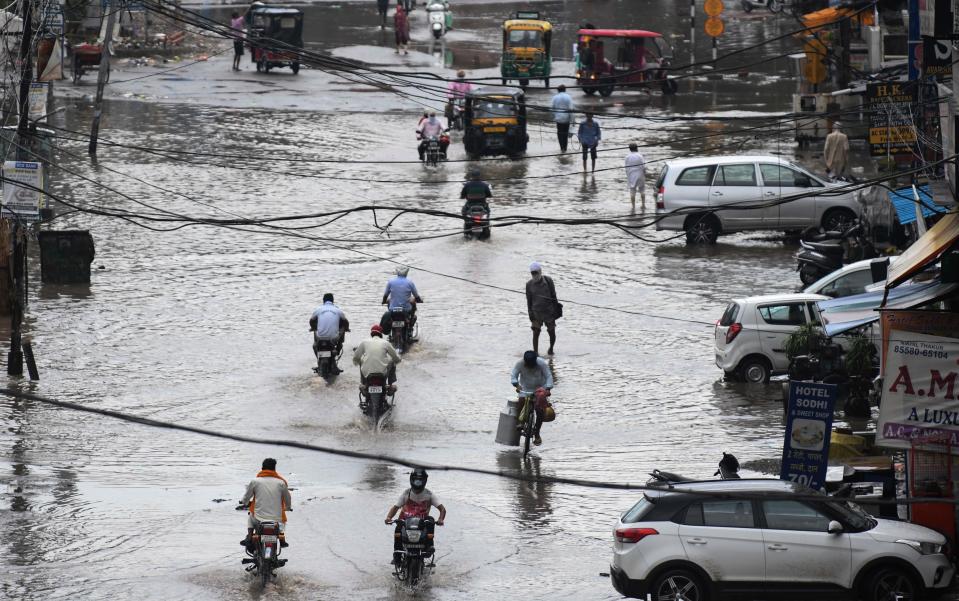 Commuters make their way along a water-logged street following heavy rains in Amritsar on July 19, 2020. (Photo by NARINDER NANU / AFP) (Photo by NARINDER NANU/AFP via Getty Images)