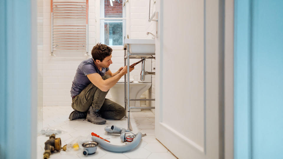 Young man fixing a leak under the bathroom sink.