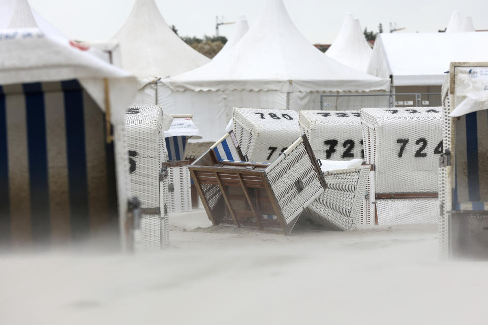 Sand sweeps across overturned beach charis during a storm in Sankt Peter Ording, northern Germany, Monday, Aug. 7, 2023. Stormy weather across the Baltic Sea region is causing airport delays, suspended ferry service, minor power outages and lots of rain. (Bodo Marks/dpa via AP)