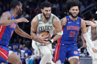 Boston Celtics forward Jayson Tatum (0) drives through Detroit Pistons guard Alec Burks, left, and forward Isaiah Livers (12), right, during the first half of an NBA basketball game, Monday, Feb. 6, 2023, in Detroit. (AP Photo/Carlos Osorio)