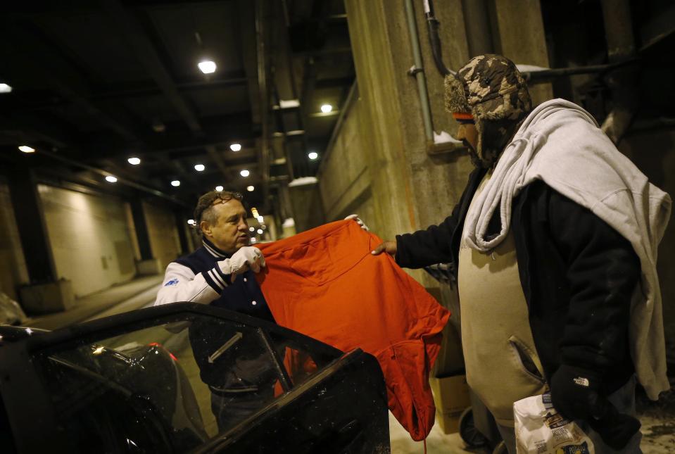 Doctor Angelo offers some clothing to a homeless man under the overpasses on Lower Wacker Drive in Chicago