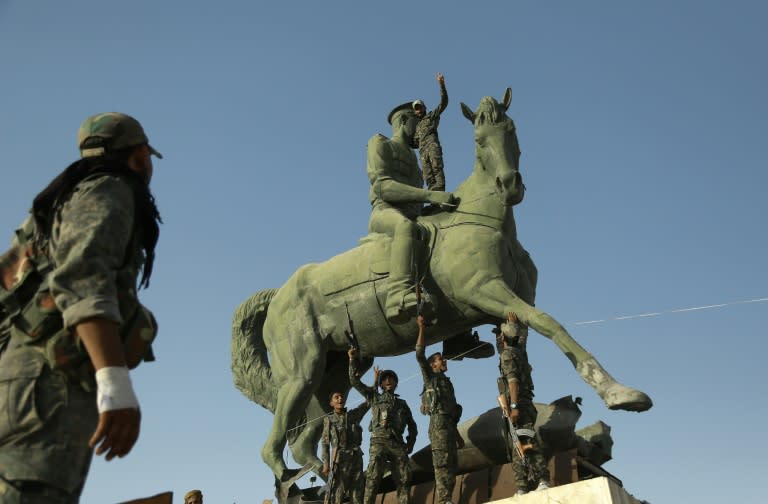 Kurdish fighters belonging to the police force -- the Asayesh -- and the People's Protection Units stand on a statue of Basel al-Assad, the late elder brother of the Syrian President, in the northeastern Syrian city of Hasakeh on August 23, 2016